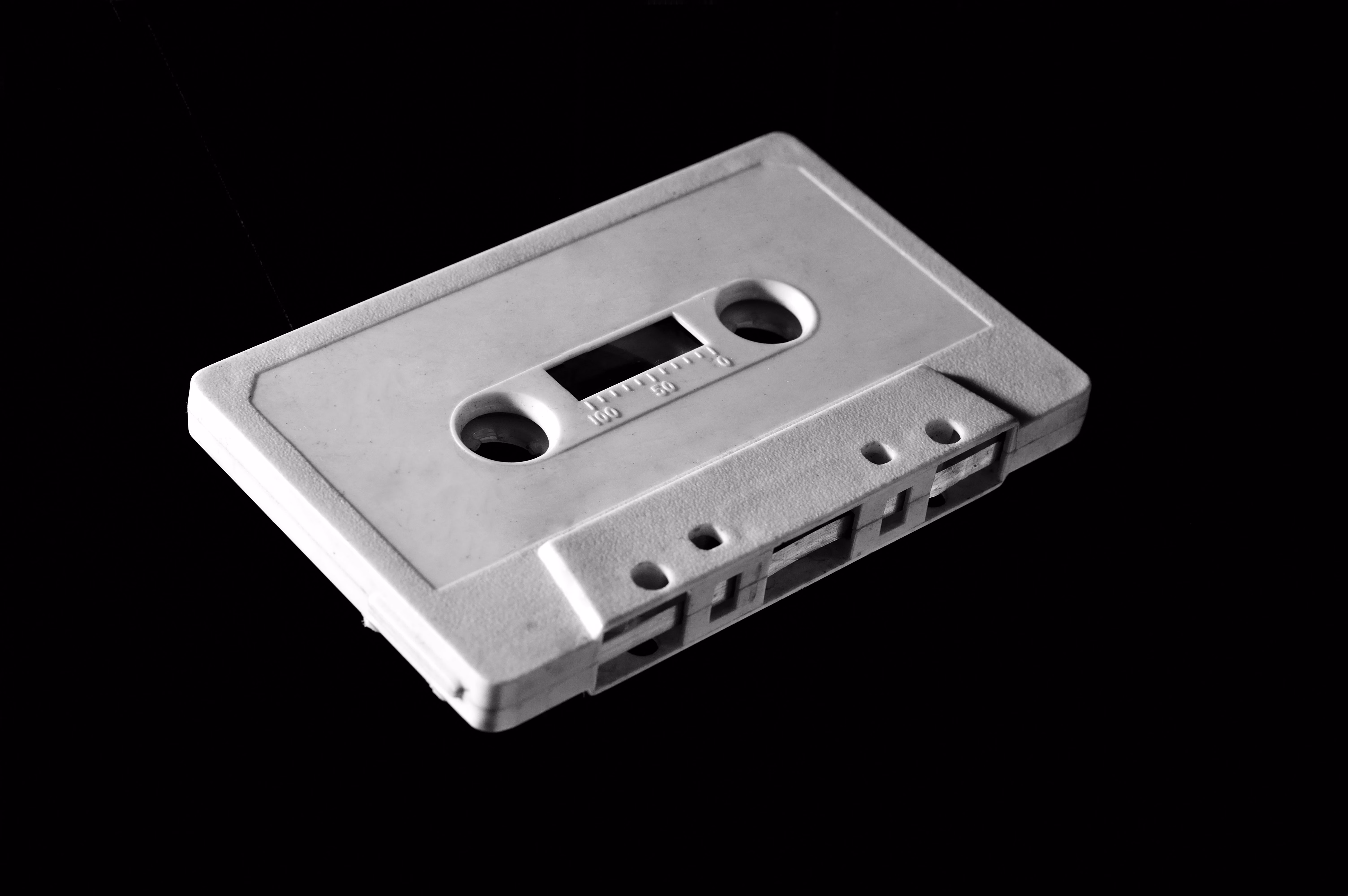 A white cassette tape is angled on a black background.