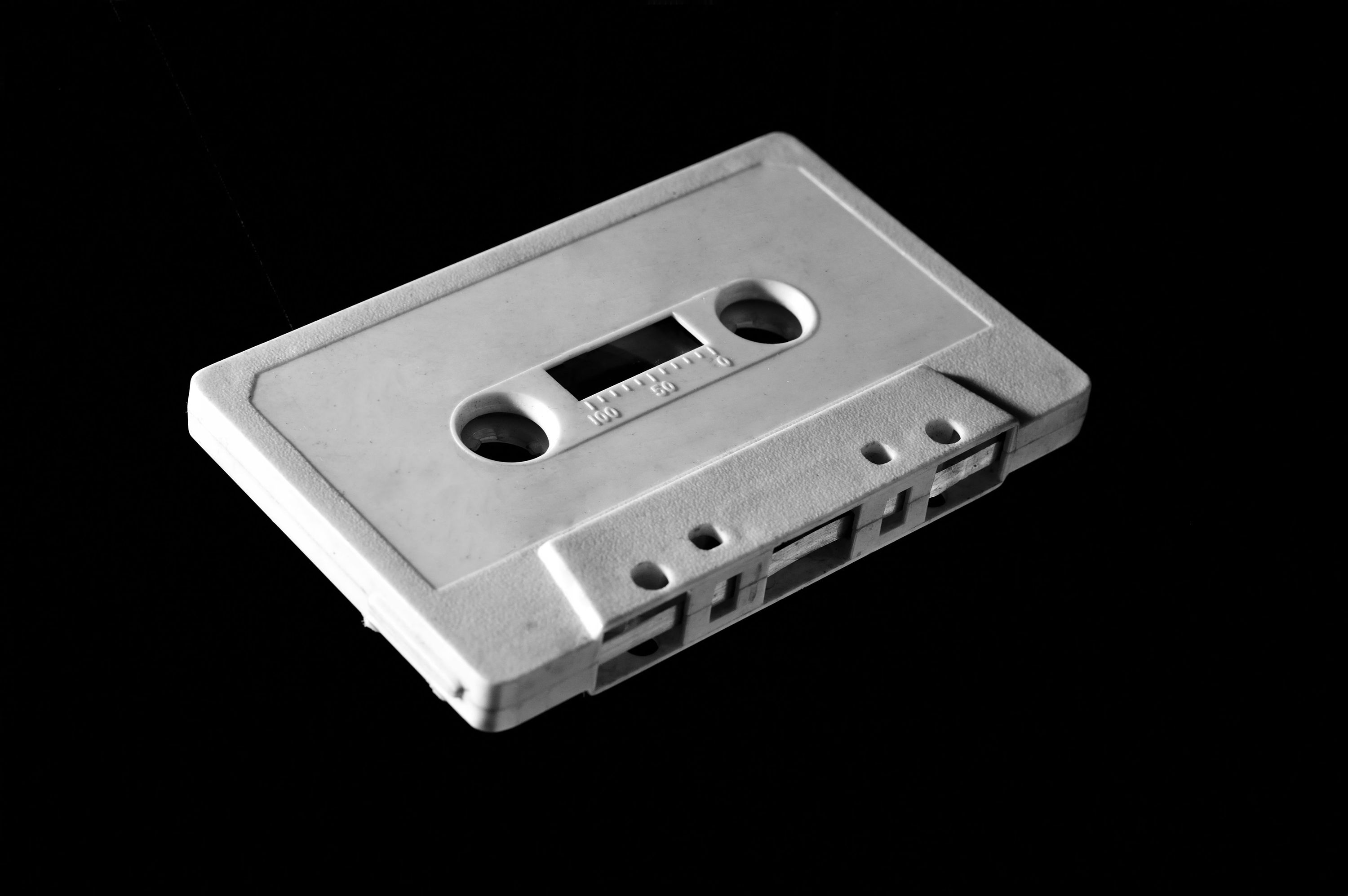 A white cassette tape is angled on a black background.